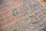 Distressed vintage Oushak rug pile texture showing faded apricot, blue, and mint motifs.