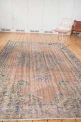 Evenly worn distressed Oushak rug corner featuring faded apricot, royal blue, and mint.