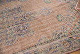 Distressed pile texture with even wear, showing faded apricot, blue, and mint curvilinear motifs.