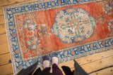 Distressed roundel medallion on bright red-orange field of vintage Oushak rug runner.