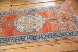 Distressed Oushak rug detail: red-orange field, blue border, and cloud band spandrel.