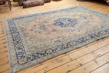 Faded apricot and navy blue field with a partial medallion on the distressed Oushak rug.