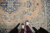 Faded apricot and navy blue traditional pattern detail on a distressed vintage Oushak rug.