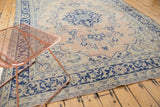 Distressed Oushak rug corner with faded apricot field and navy blue border patterns.