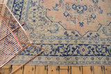 Distressed Oushak rug's lower border, faded apricot field, navy and beige patterns.