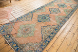 Detailed view of blush and mint medallions on a distressed vintage Oushak runner.