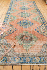 Distressed Oushak runner displaying worn peach pile, mint green, and sky blue medallions.