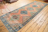 Distressed blush Oushak rug with mint and sky blue medallion, and ornate blue border.