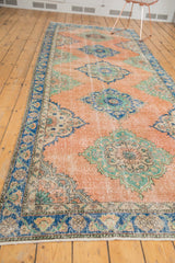 Distressed vintage Oushak runner in blush peach with mint green and sky blue medallions.