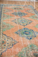 Distressed vintage Oushak runner, highlighting worn peach field and blue-mint medallion motifs.