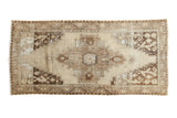 Distressed vintage Oushak runner, beige and brown, with an oversized medallion and visible wear.