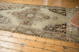 Distressed Oushak runner corner with mostly even wear, exposed foundation, and scrolling tendrils.