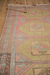 Distressed texture of a vintage Oushak runner with sage, blush, and cinnabar geometric guls.