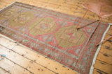 Distressed vintage Oushak runner end, showing its worn pile and geometric guls in red, green, silver.