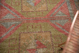 Distressed texture and geometric pattern detail of vintage Oushak rug, cinnabar red, sage, silver.