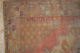 Vintage Oushak corner showing faded cinnabar and tangerine lattice patterns, even wear, and fringe.