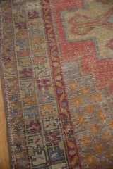 Distressed vintage Oushak rug with worn pile, intact selvage, and muted colors.