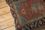 Antique Heriz runner corner detail: madder red field, aqua spandrel, floral motifs, and selvage tatter.