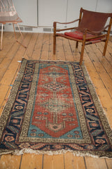 Tattered fringe and sharp serrated aqua blue corner spandrel of an antique Heriz runner.