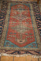 Antique Persian Heriz runner's worn end finial, featuring aqua spandrel and floral motifs.