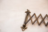 Antique fleur de lis hardware detail and accordion arm with darkened patina.