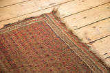 Antique Belouch rug's tattered fringe and worn side border with madder red, brown, ivory geometric stripes.