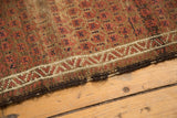 Antique Belouch rug with madder root red, ivory geometric border and visible tattered edge.
