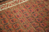 Antique Belouch rug pile: madder root red, coffee brown, blue, ivory geometric patterns.