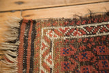 Tattered fringe, striped brown and red edge, with geometric pattern on a Belouch rug.