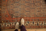 Antique Northwest Persian rug's worn floral boteh field transitions to madder red border.