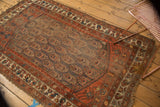 Worn lower corner of antique Northwest Persian rug showing faded red and ivory borders.