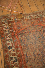 Detail of antique Northwest Persian rug: worn madder root field, navy botehs, exposed foundation, tattered fringe.