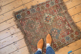 Hard wear and geometric starbursts on an antique Caucasian fragment rug with tattered fringe.