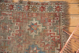 Antique Caucasian rug corner with hard wear, visible foundation, and tattered fringe.