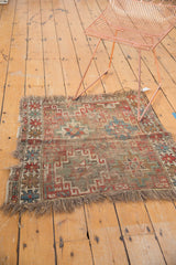 Tattered fringe and worn corner of antique Caucasian fragment rug with red, blue geometrics.