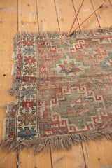 Worn edge of the antique Caucasian fragment rug showing tattered fringe and exposed weave.