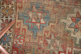 Geometric starburst and serpent motifs with prominent foundation wear on antique Caucasian fragment.