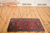 Detail of antique Lilihan rug's cherry red field with floral cross-sections and tattered fringe.