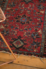 Antique Lilihan rug featuring cherry red field, navy floral diamond motif, and tattered edge.
