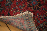 Folded corner of hand-knotted Antique Lilihan rug, showing cherry red pile, worn fringe, and woven backing.