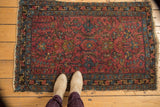 Vintage Lilihan rug corner with raspberry red field, sky blue border, serrated leaves, and tattered fringe.