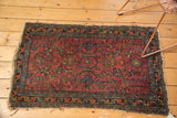 Vintage Lilihan rug's corner with tattered ends, showing raspberry field and sky blue border.