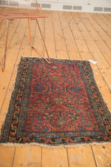 Vintage Lilihan rug's tattered fringe and detailed border with raspberry red and blue floral patterns.