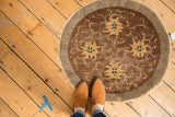 Antique Peking round rug with whimsical gold floral motifs, visible wear, and tattered fringe.