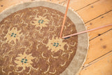 Textured pile of antique Peking rug showing whimsical gold florals, green centers, and tattered edge.
