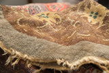Antique Peking rug's worn pile with exposed foundation, light tatter, camel, and green-blue motifs.