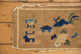 Tattered fringe and pictorial indigo motifs on corner of antique Peking rug mat.