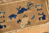 Antique Chinese pictorial rug's low pile, tattered edge, and camel and indigo motifs.