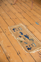 Pictorial indigo blue motifs, low pile, and tattered edges on this antique Chinese rug mat.