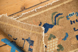 Close-up: Woven back and tattered edge of antique Chinese rug mat with camel, blue motifs.